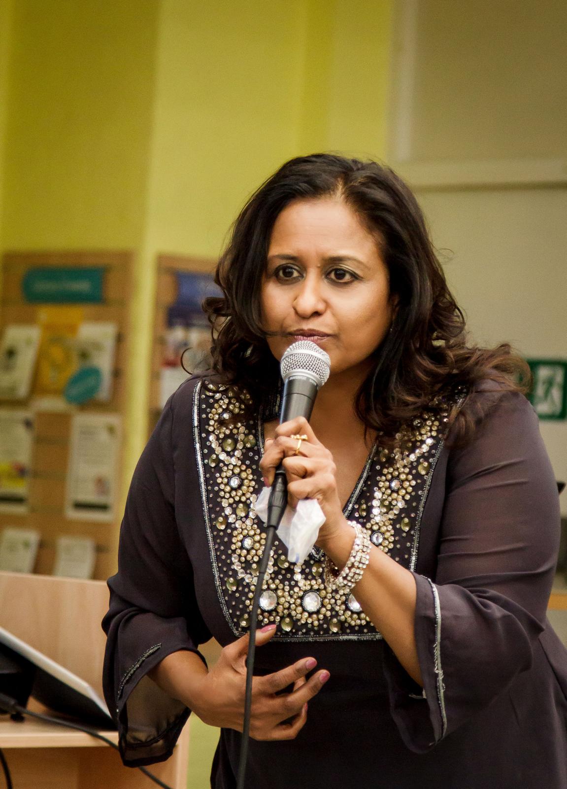 Usha Oliver speaking with a microphone at a UK event